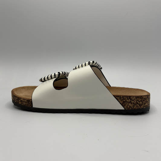 White sandal with brown sole on a gray background