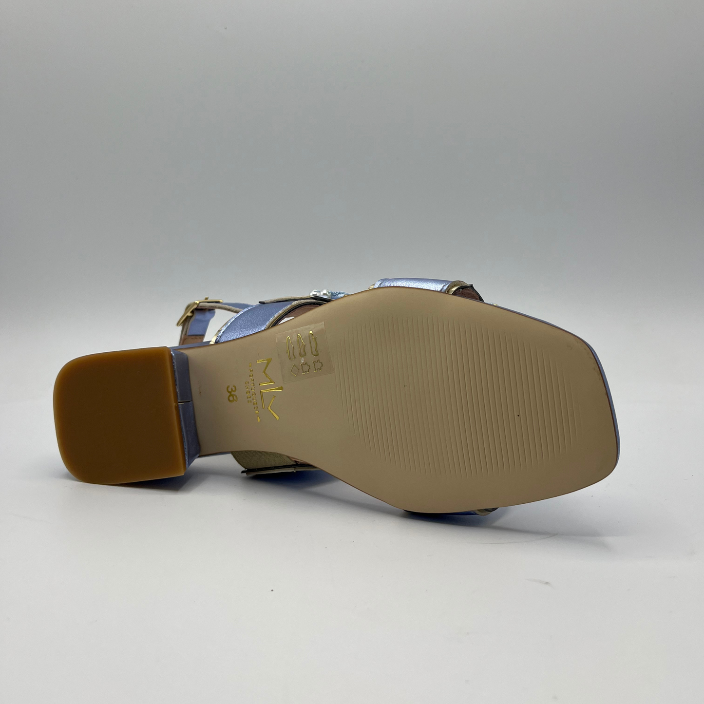 Bottom view of a blue metallic leather sandal with a leather lining and upper. Large buckle straps and one delicate sling back strap. Low block heel and delicate pearl details on the buckles.