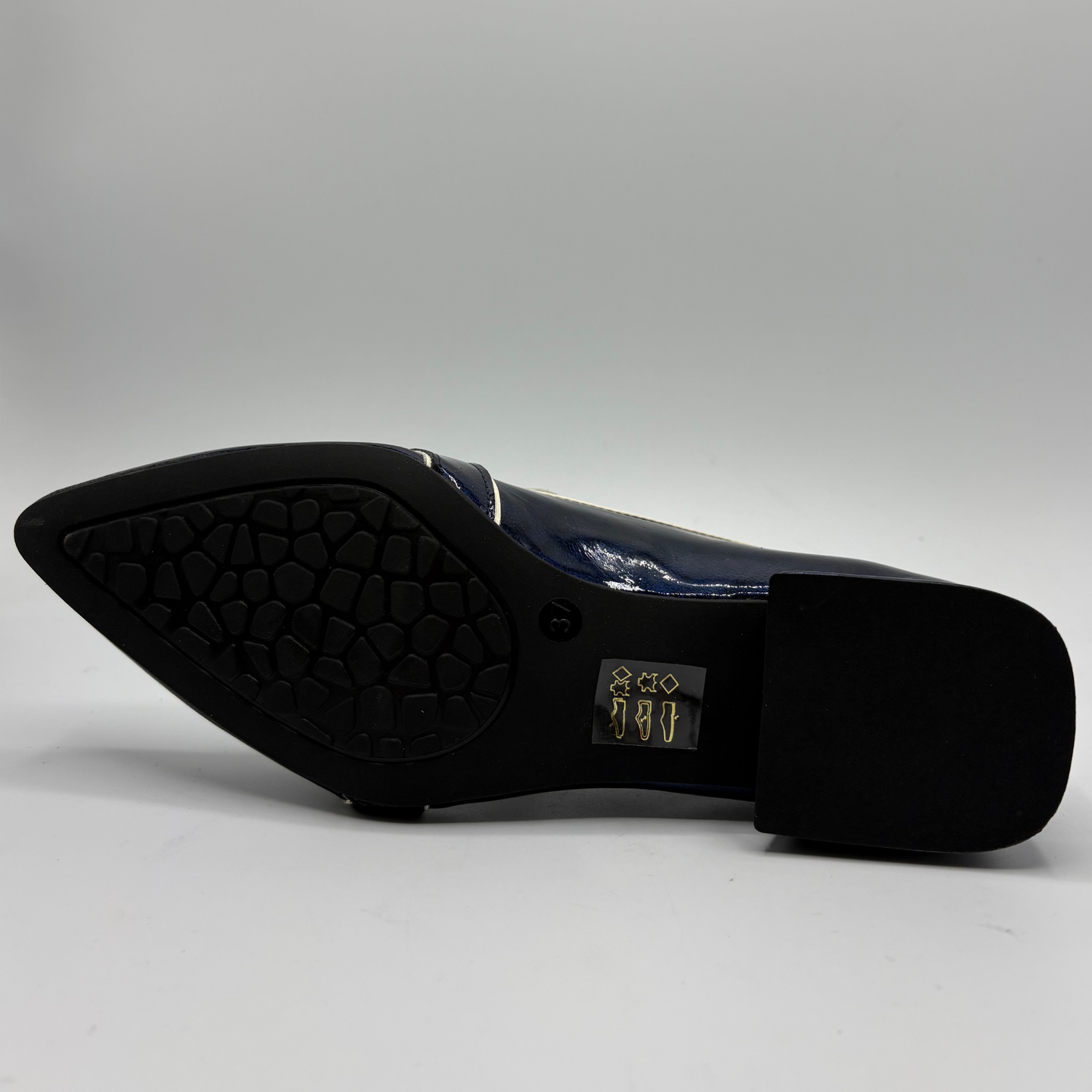 Bottom view of a dark blue patent leather loafer with a pointed toe and a buckle strap accent