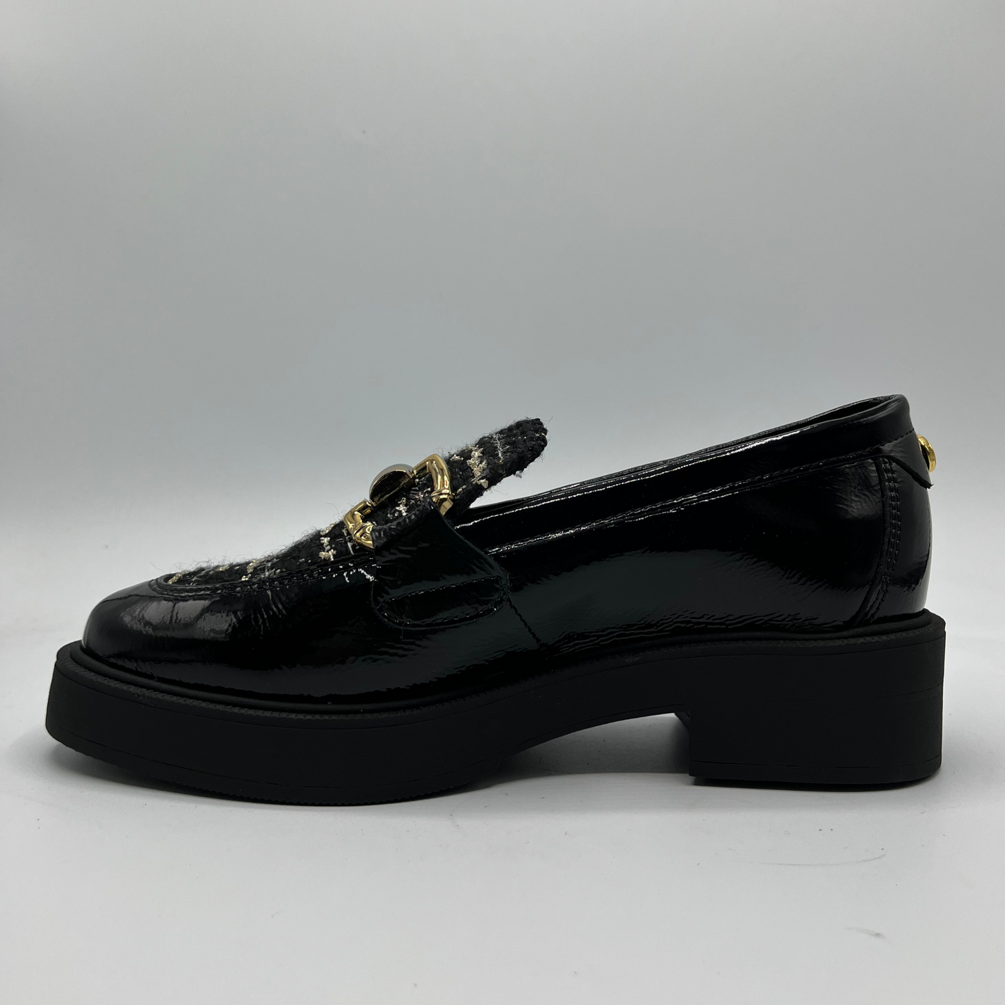 Black loafers with decorative elements on a gray background
