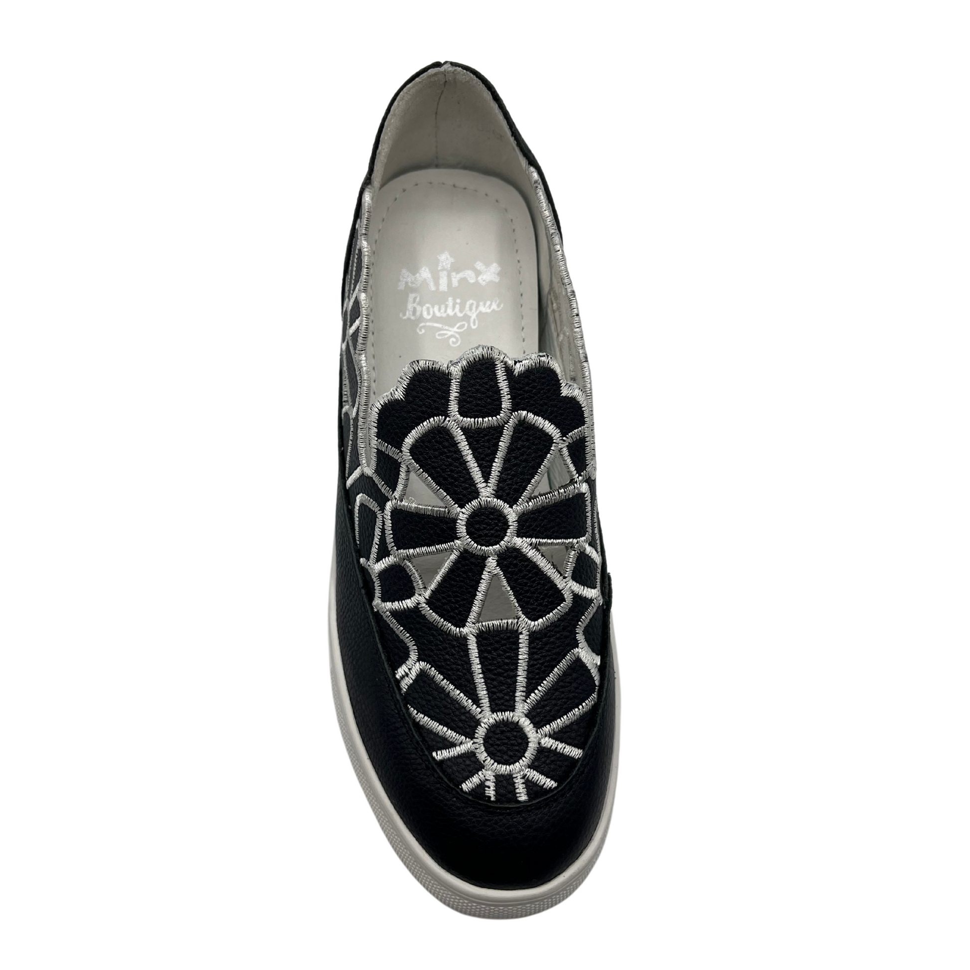 Top view of leather wedge sneaker with hidden wedge, cut out and embroidered upper and white rubber outsole.