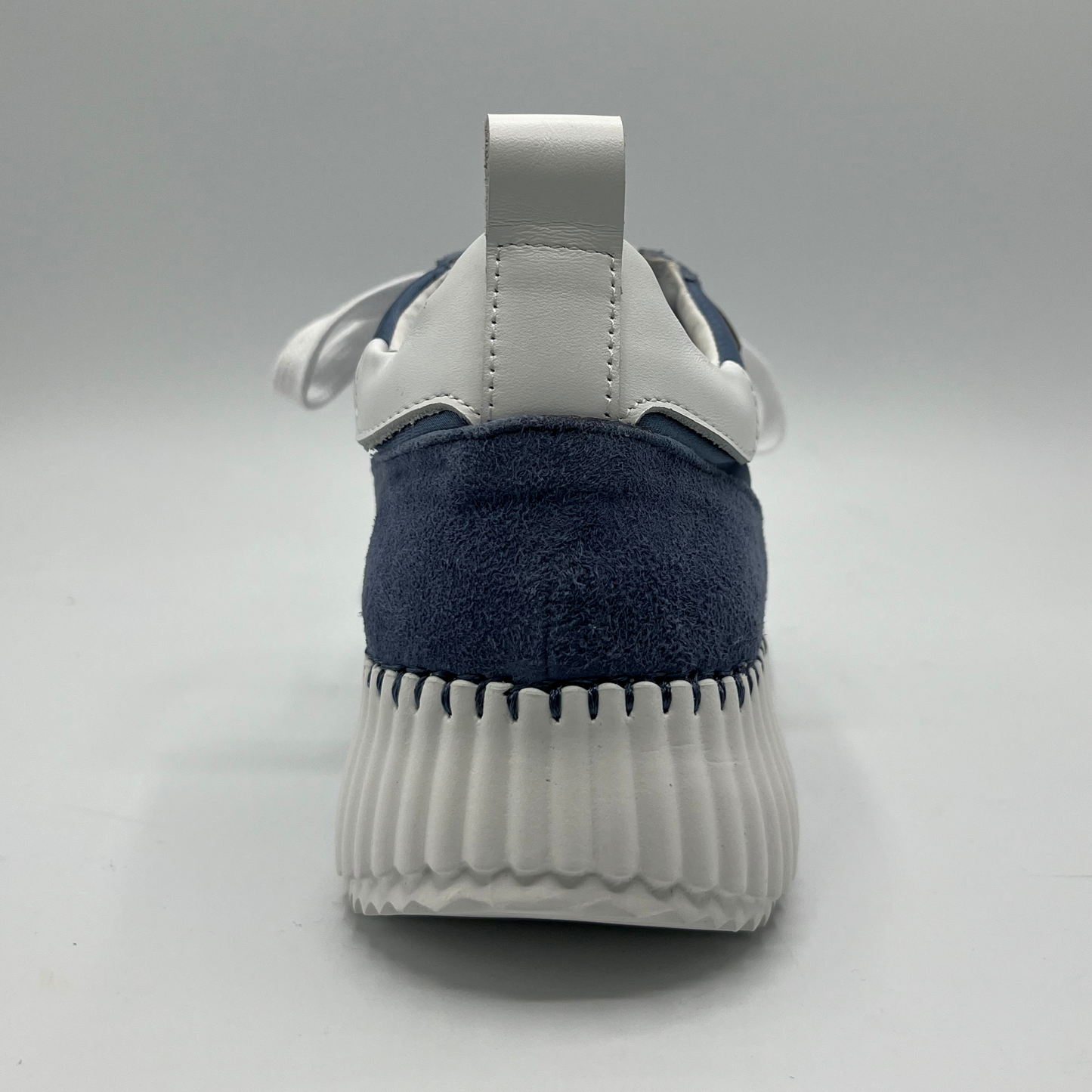 Back view of a denim suede sneaker with a white rubber platform outsole and white laces