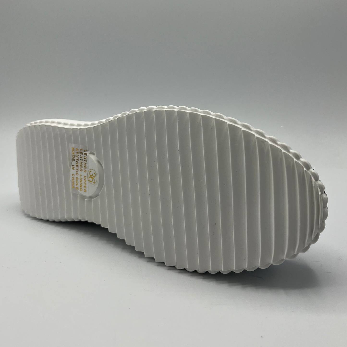 Bottom view of a denim suede sneaker with a white rubber platform outsole and white laces