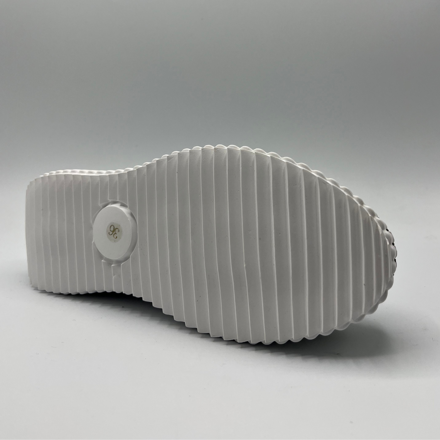 Bottom view of a khaki green sneaker made from leather and suede with a thick white platform outsole. Featuring faux pearl details around upper.