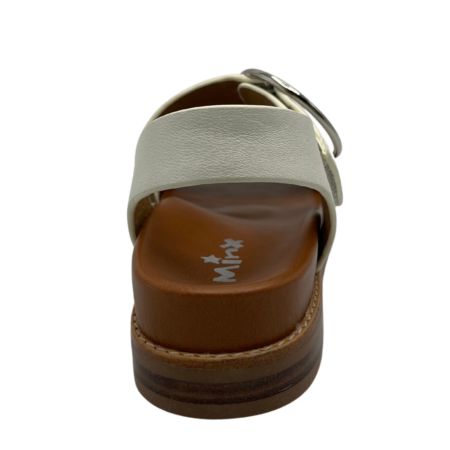 Back view of white leather strapped sandals with tan leather lining. Large round silver buckle and low heel