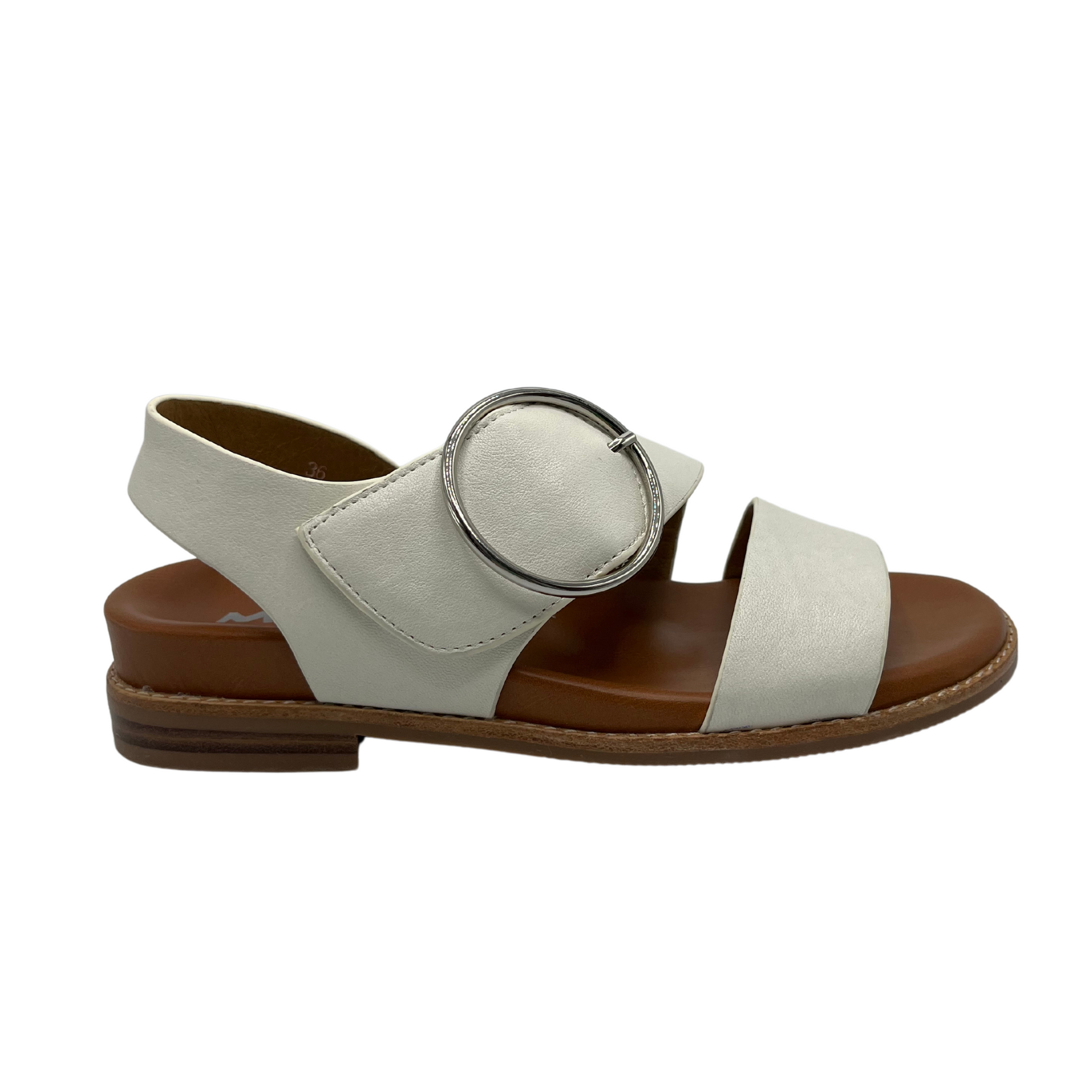 Right facing view of white leather strapped sandals with tan leather lining. Large round silver buckle and low heel