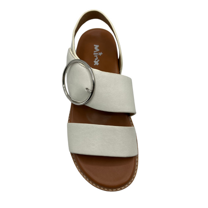 Top view of white leather strapped sandals with tan leather lining. Large round silver buckle and low heel