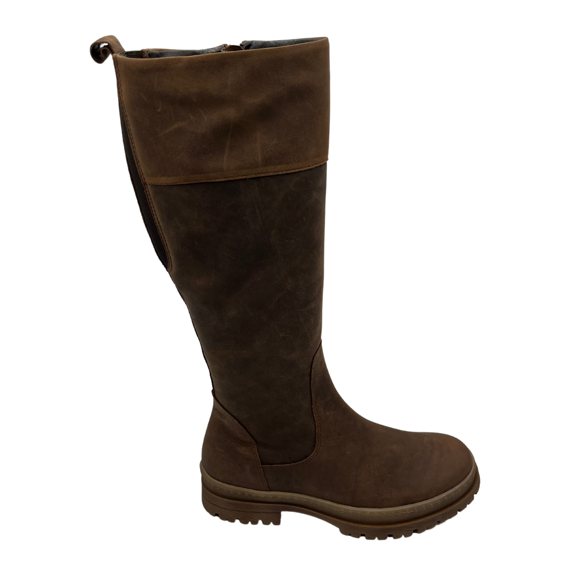 Right facing view of brown leather knee height boot with rubber lug outsole, inside zipper and pull on tab