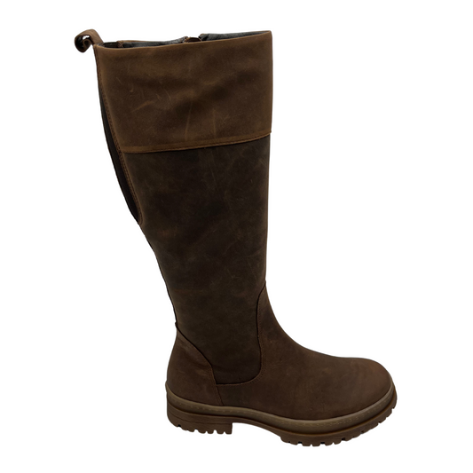 Right facing view of brown leather knee height boot with rubber lug outsole, inside zipper and pull on tab