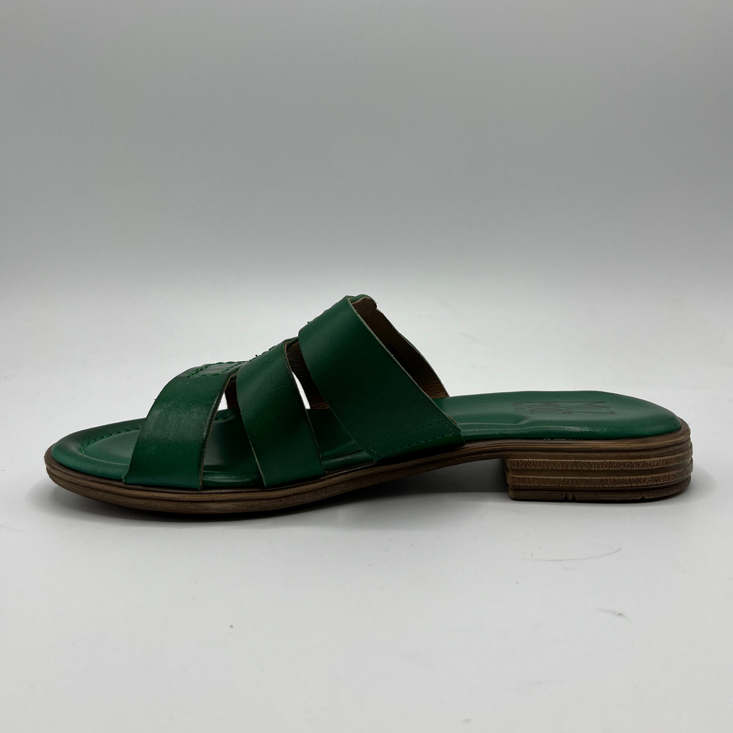Left facing view of a leather slip on sandal in emerald green with a low stacked heel, and cushioned leather lined insole