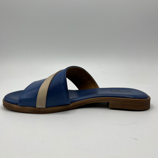 Left facing view of denim blue leather slip on sandal with a cushioned, leather lined insole and a decorative cream coloured buckle strap.