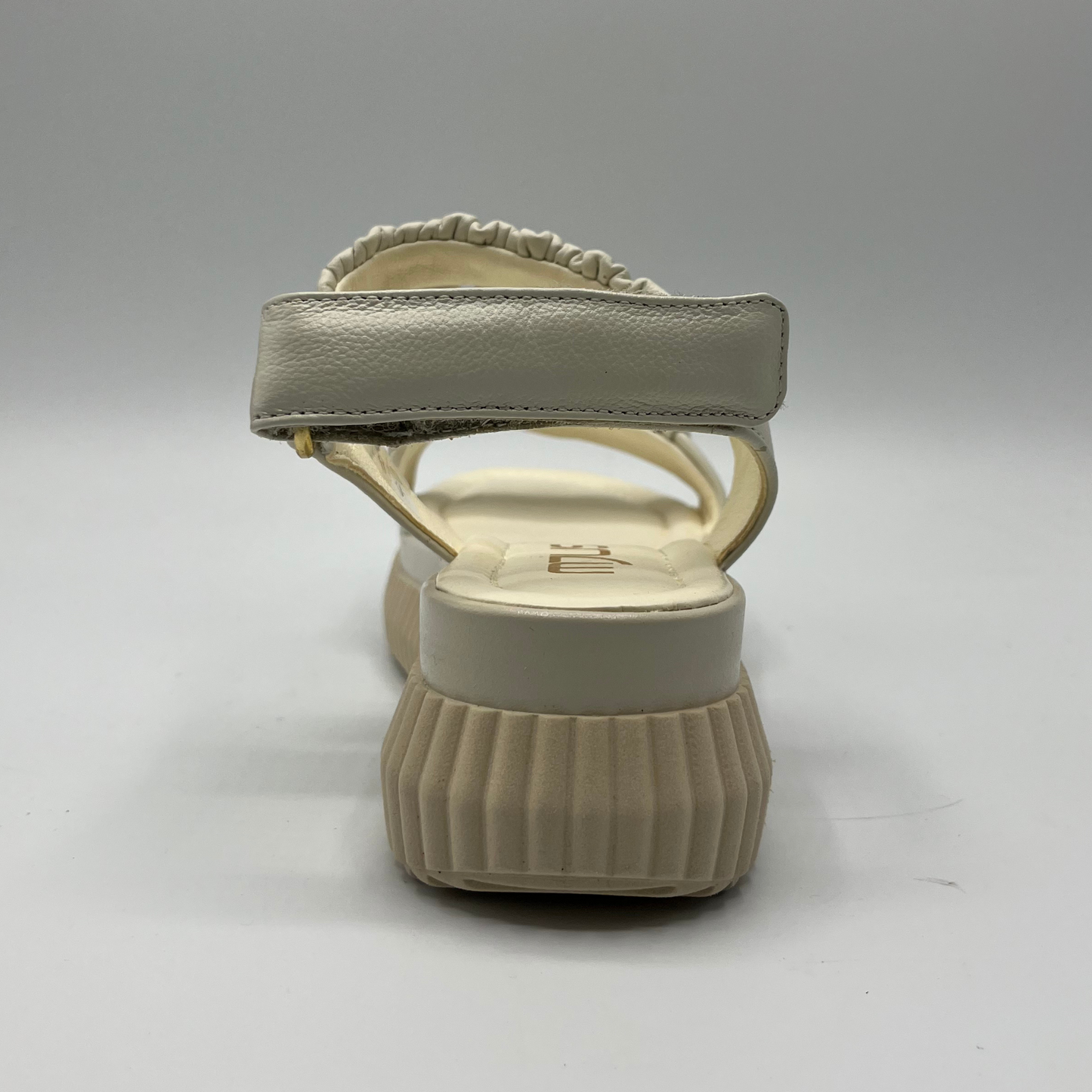 Back view of an ivory coloured leather sandal with a thick platform outsole and an adjustable sling back strap.