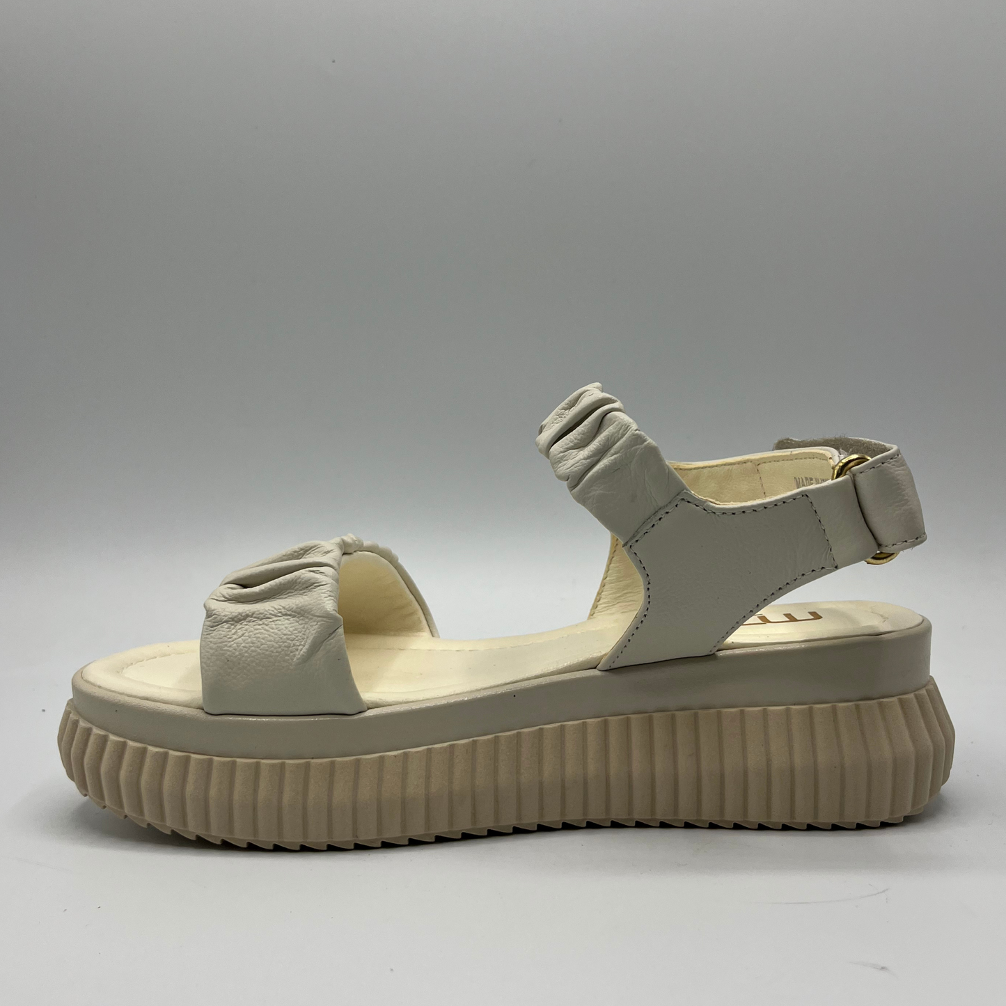 Left facing view of an ivory coloured leather sandal with a thick platform outsole and an adjustable sling back strap.