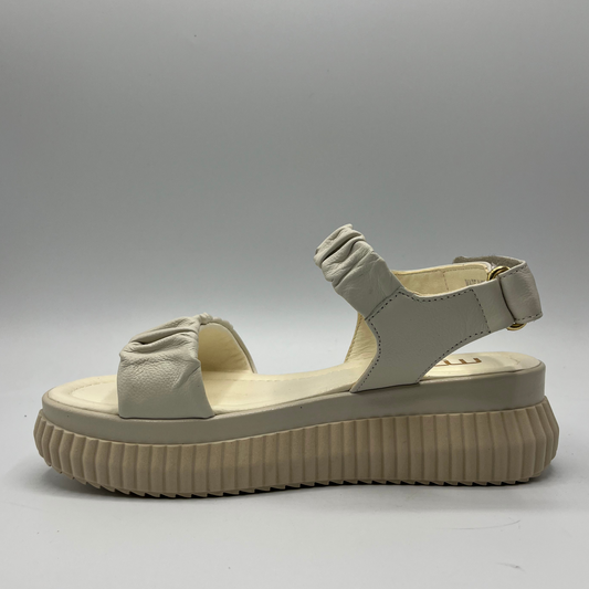 Left facing view of an ivory coloured leather sandal with a thick platform outsole and an adjustable sling back strap.