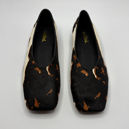 Pair of cow print patterned shoes on a white background