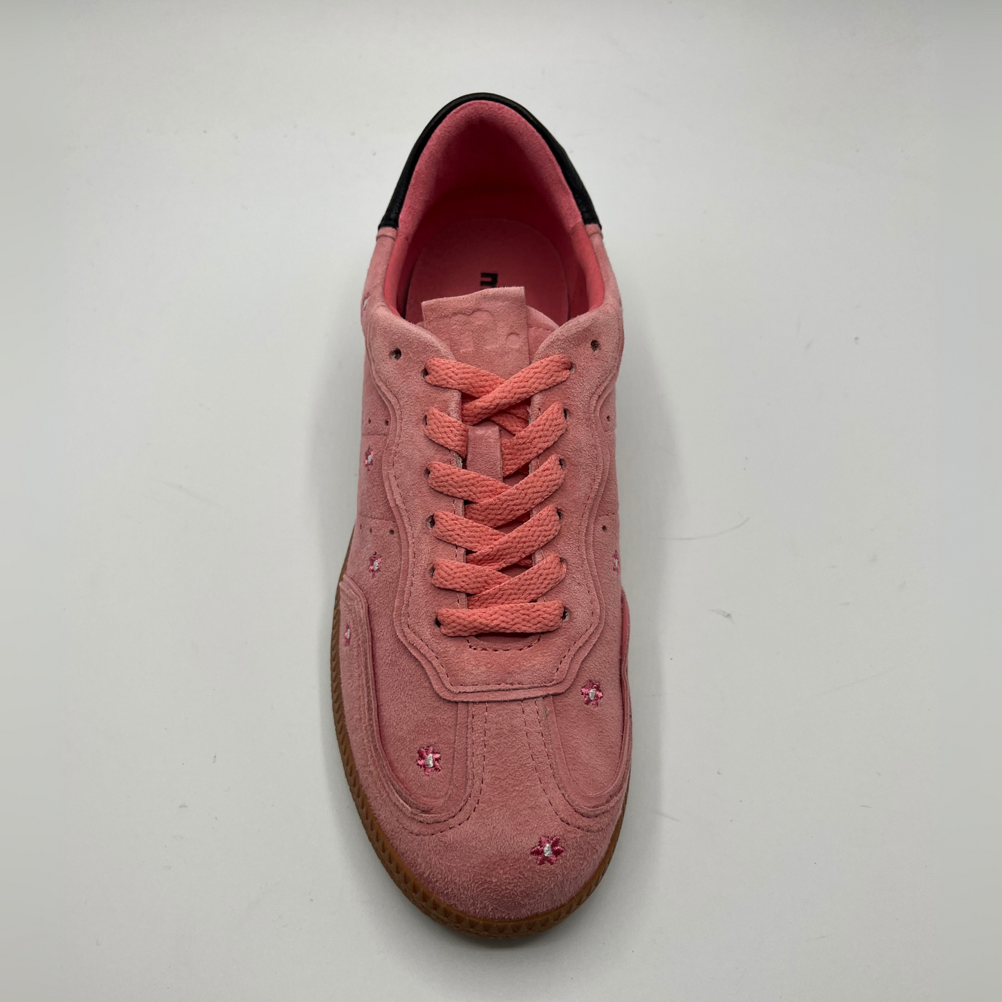 Top view of a pink suede sneaker with a black collar and a tan rubber outsole.