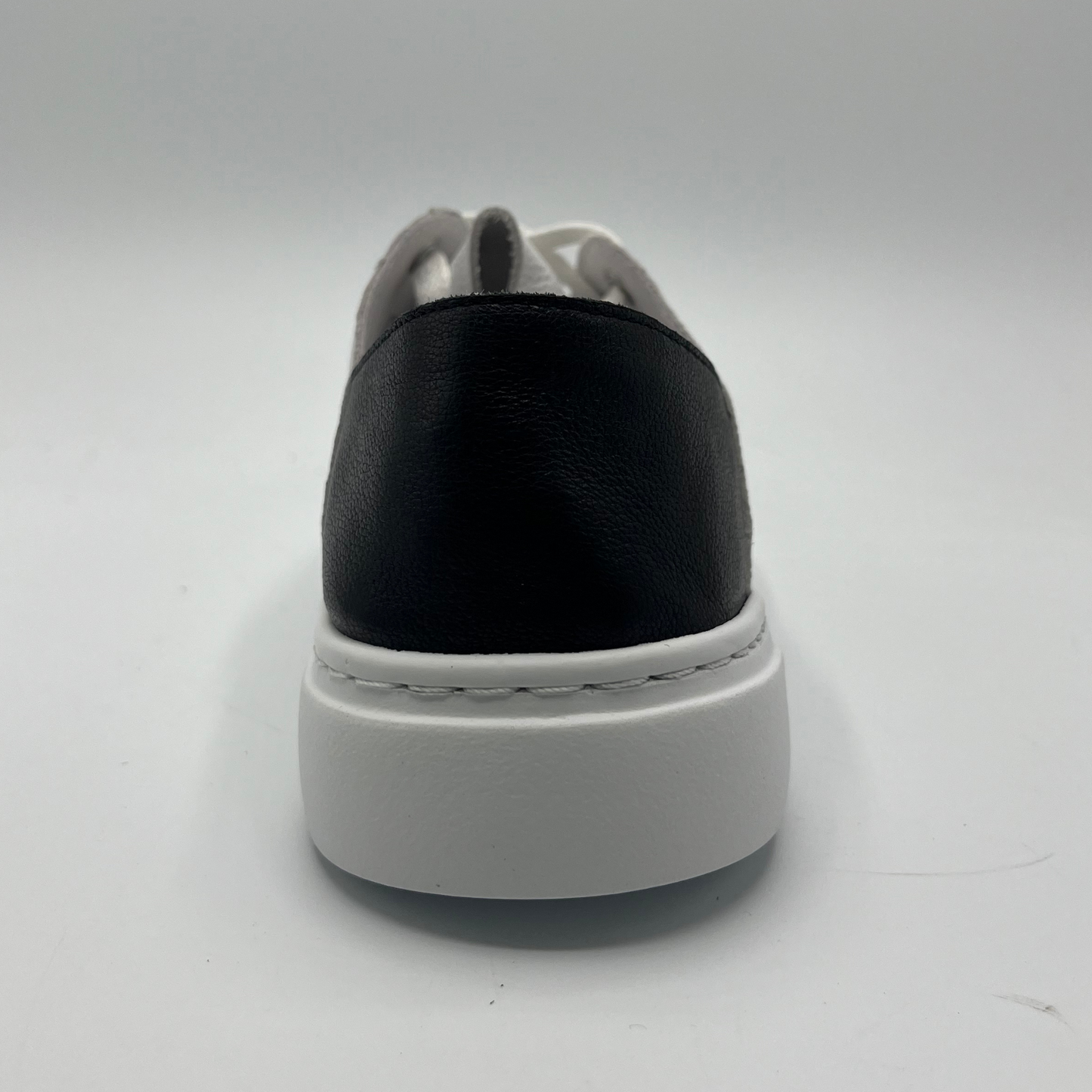 Back view of a white leather sneaker with a black heel