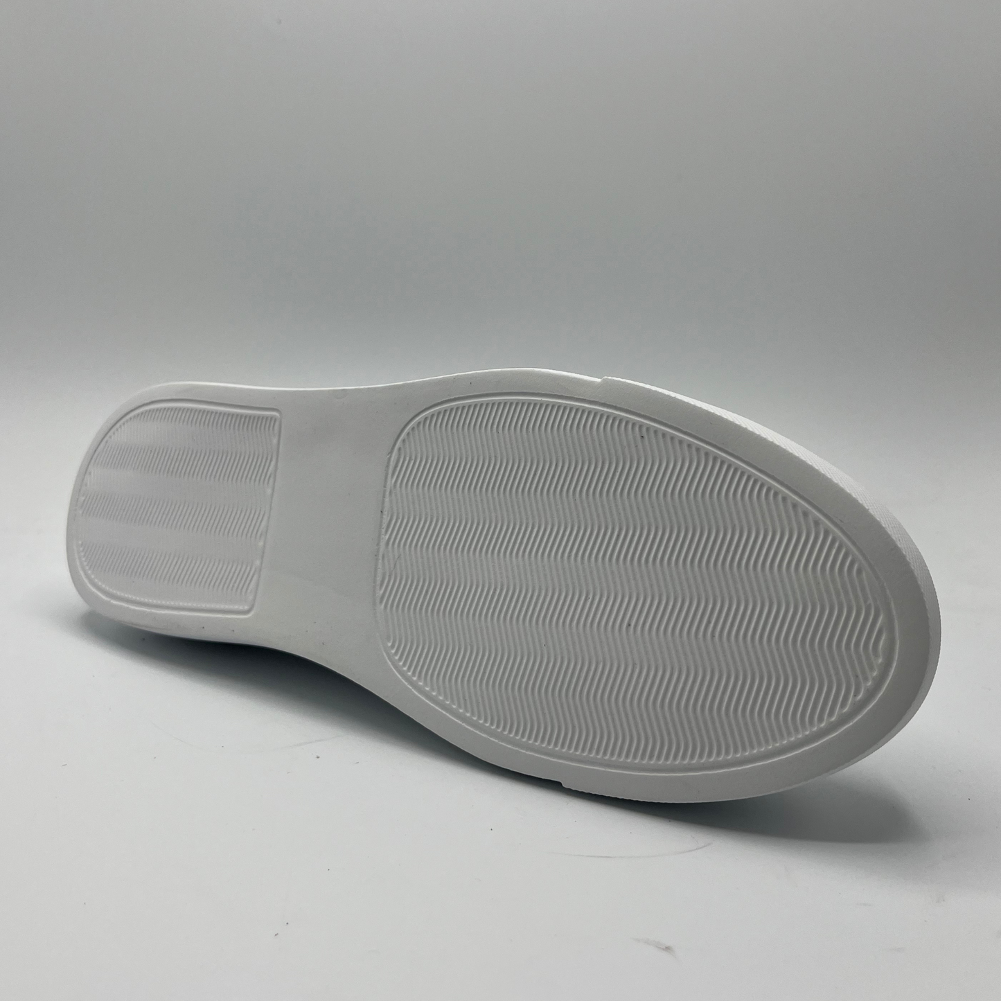 Bottom view of a leather sneaker with a white rubber outsole