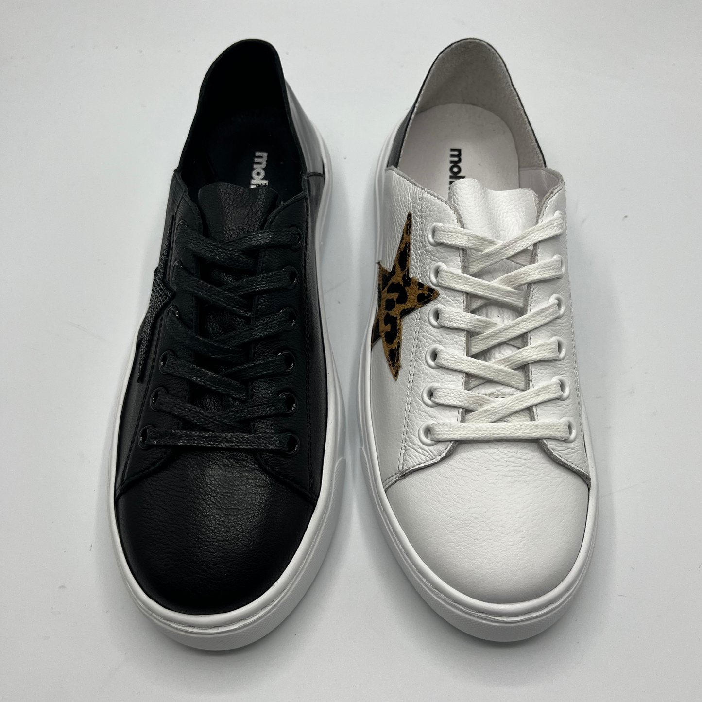 Top view of a black sneaker and a white leather sneaker
