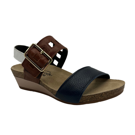 45 degree angled view of leather sandal with a large buckle strap with low wedge heel