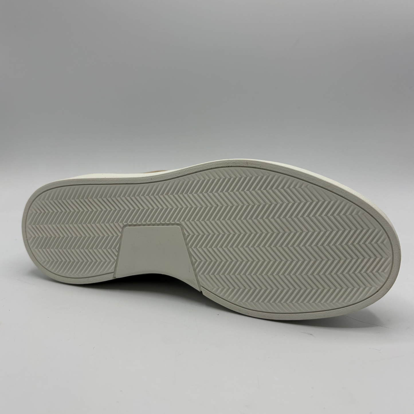 Bottom view of an almond, black and white sneaker with laces and a side zipper