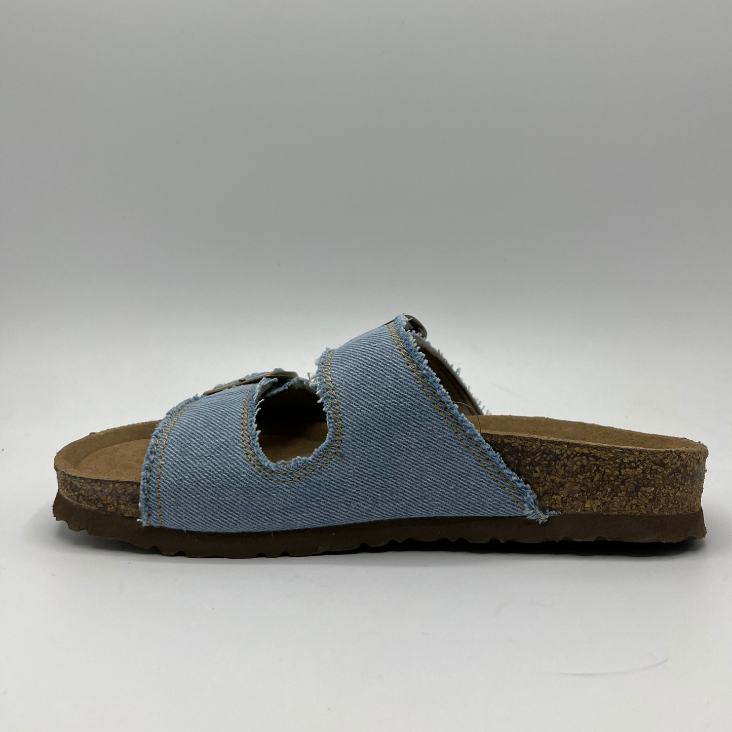 Left facing view of a denim slip on sandal with a contoured cork footbed and two adjustable straps.