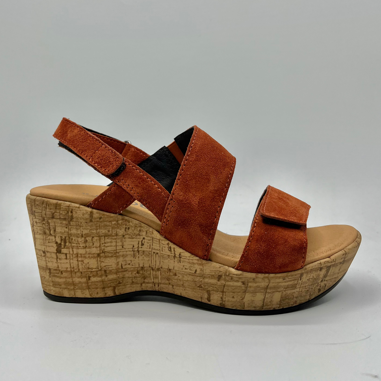 Right facing view of a suede sandal with a cushioned footed and hook and loop adjustable straps on the ankle and toe.