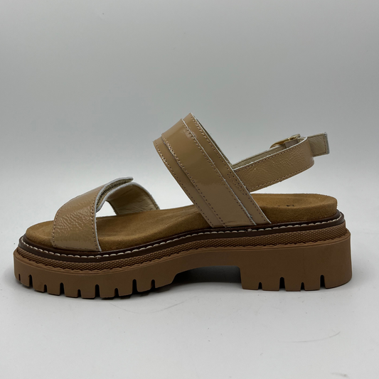 Left facing view of a camel coloured sandal with a matching lug rubber outsole. Adjustable buckles and hook and loop closures.