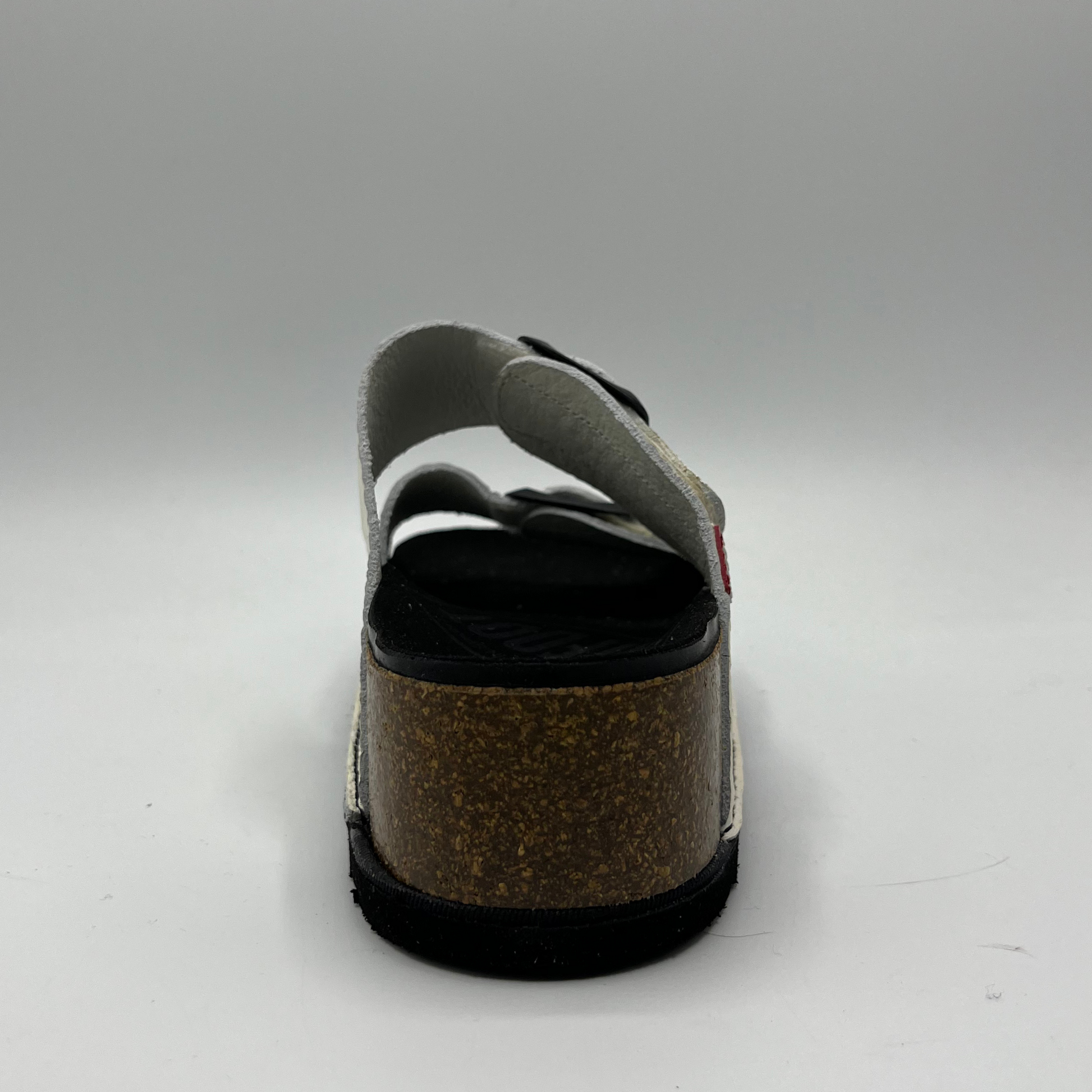 Back view of a platform sandal in a pebbled white leather.  Two thick straps across with adjustable buckles.