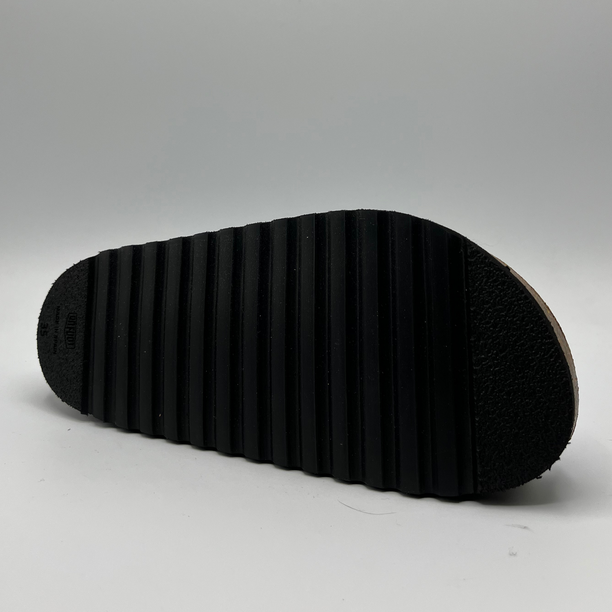 Bottom view of a platform sandal in a pebbled white leather.  Two thick straps across with adjustable buckles.