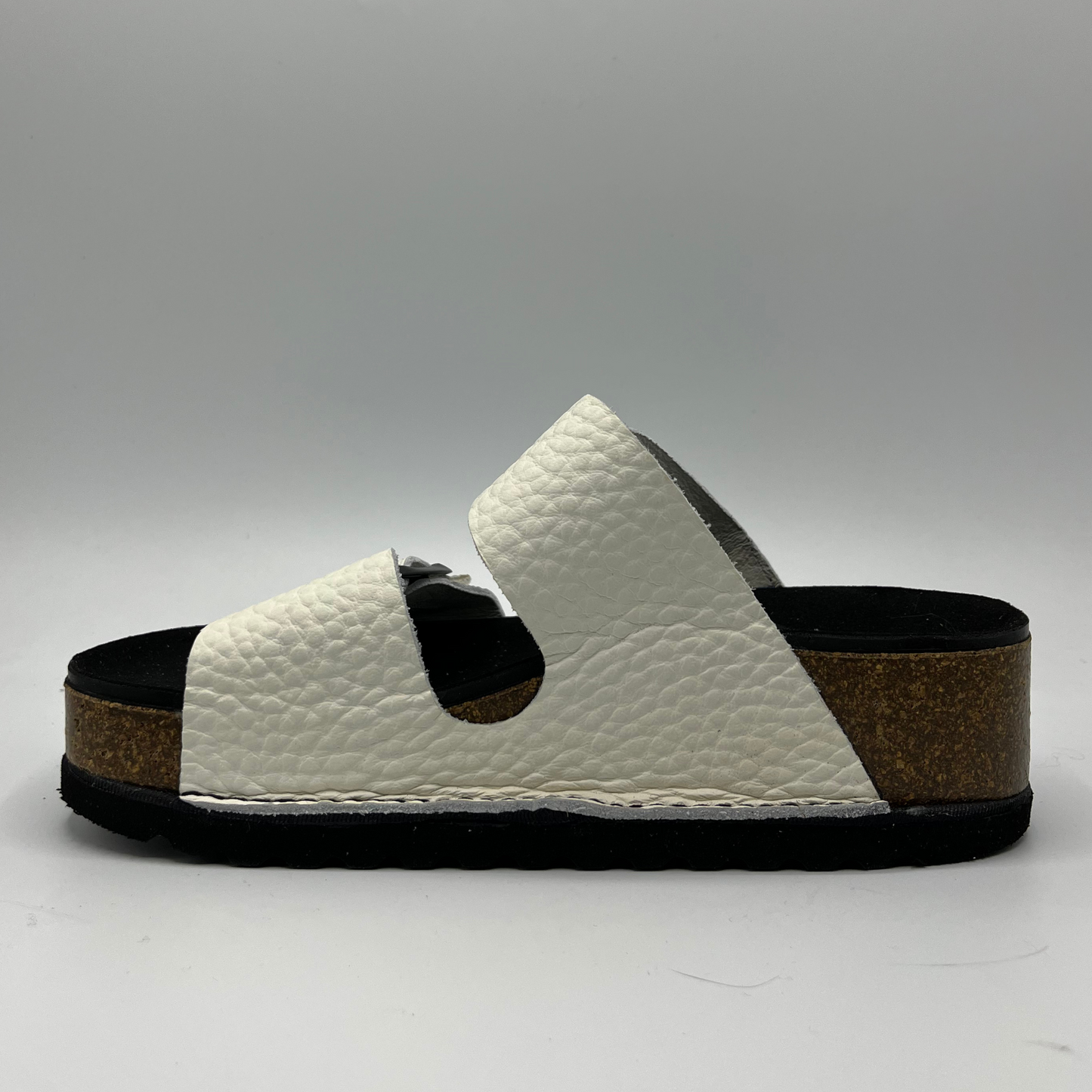Left facing view of a platform sandal in a pebbled white leather. Two thick straps across with adjustable buckles.