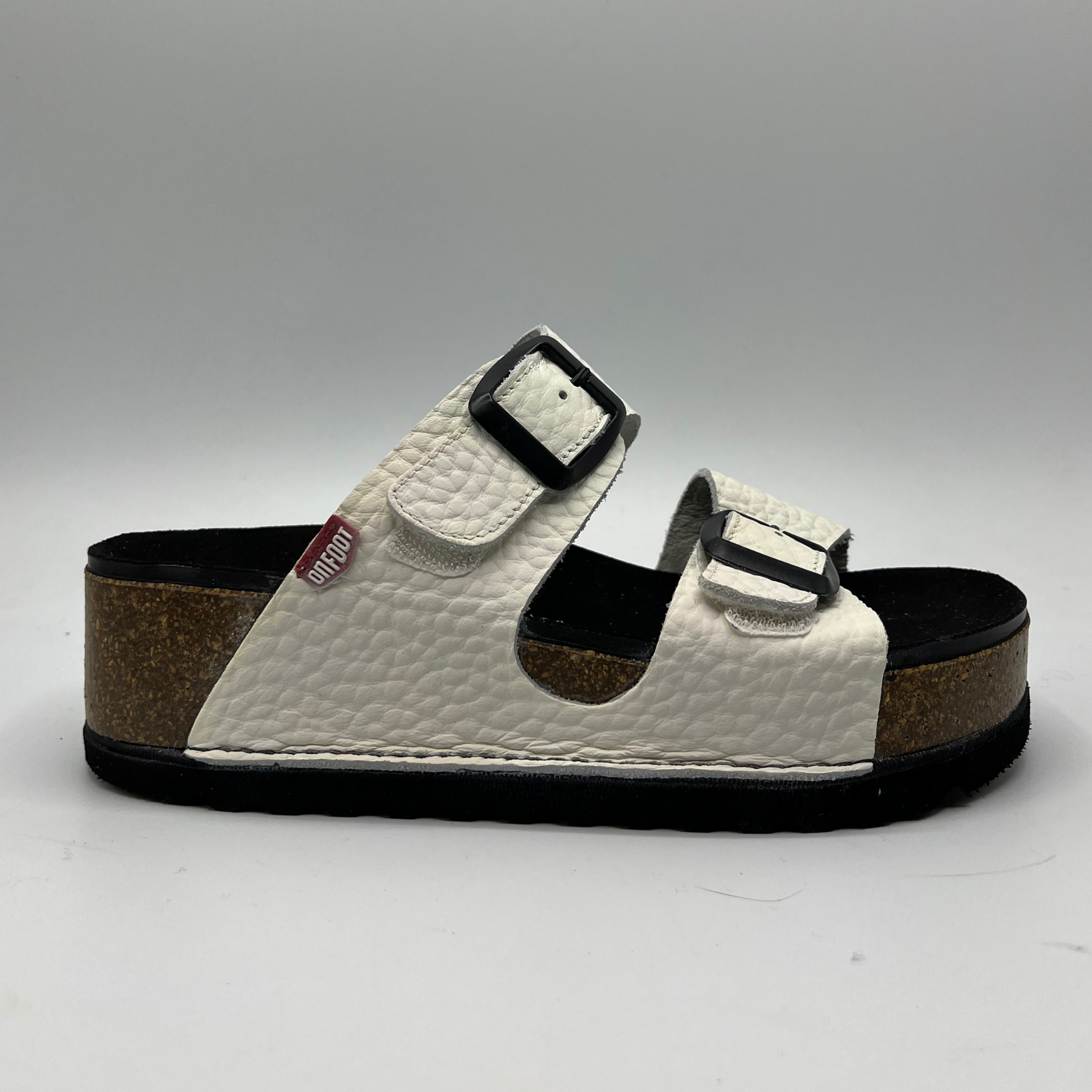 Right facing view of a platform sandal in a pebbled white leather.  Two thick straps across with adjustable buckles.