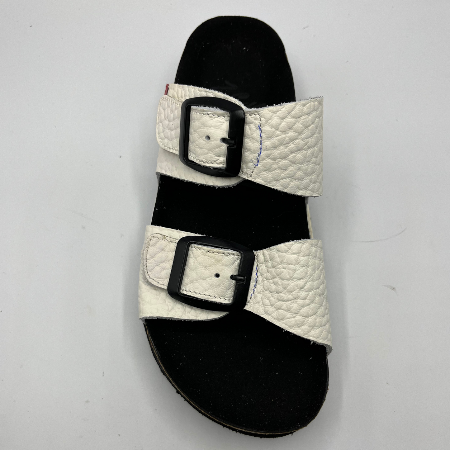 Top down view of a platform sandal in a pebbled white leather. Two thick straps across with adjustable buckles.