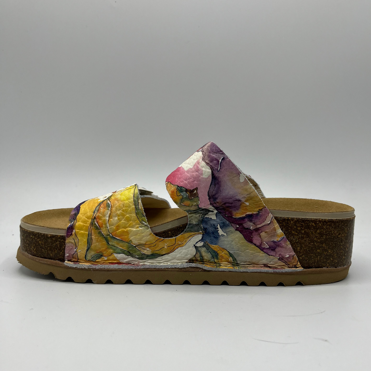 Left facing view of a leather strapped sandal with a floral watercolour pattern, two adjustable straps and a contoured footbed.