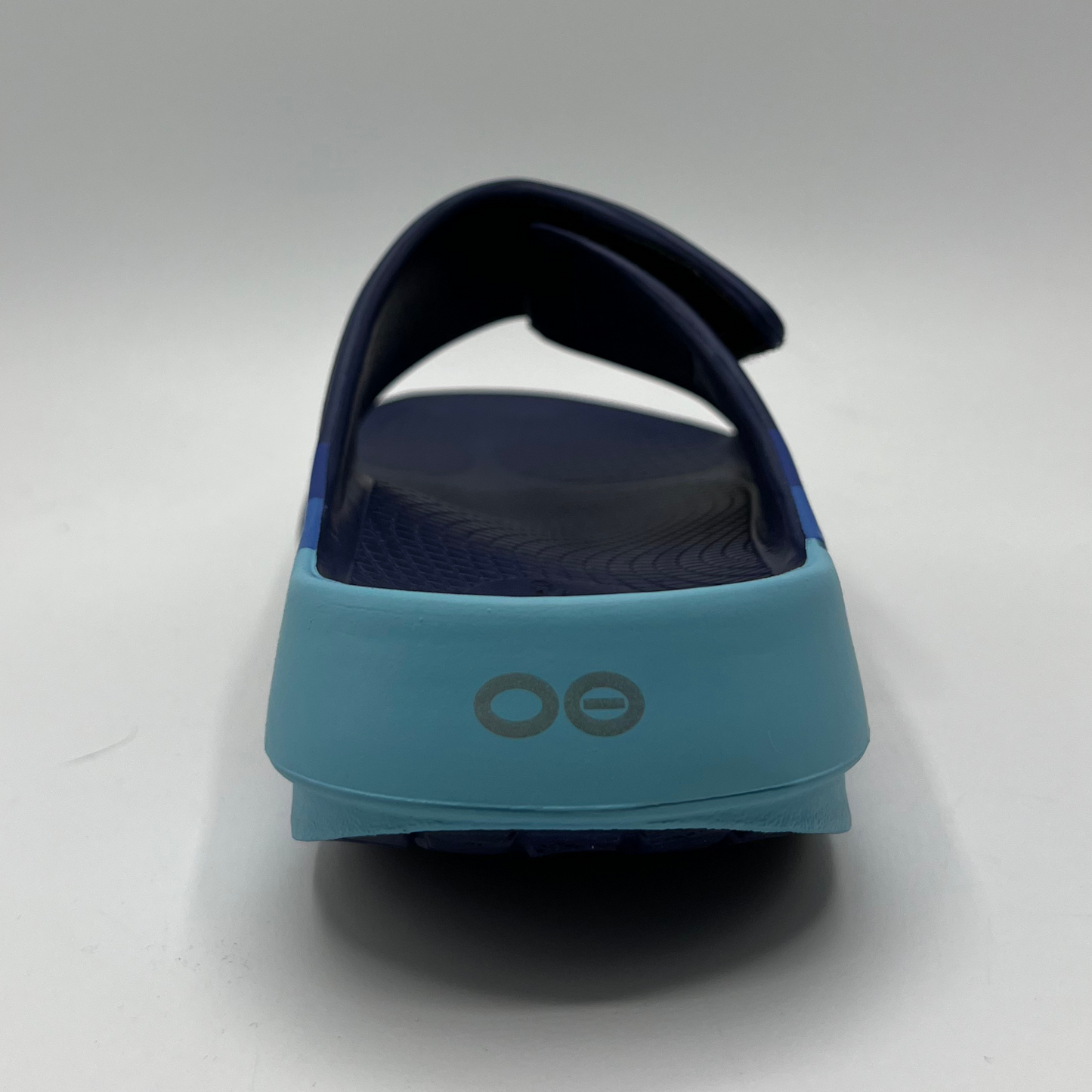 Back view of a blue multi-toned foam unisex sandal with an adjustable slip on strap.