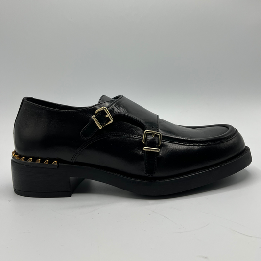 Black leather shoe with gold buckles on a white background