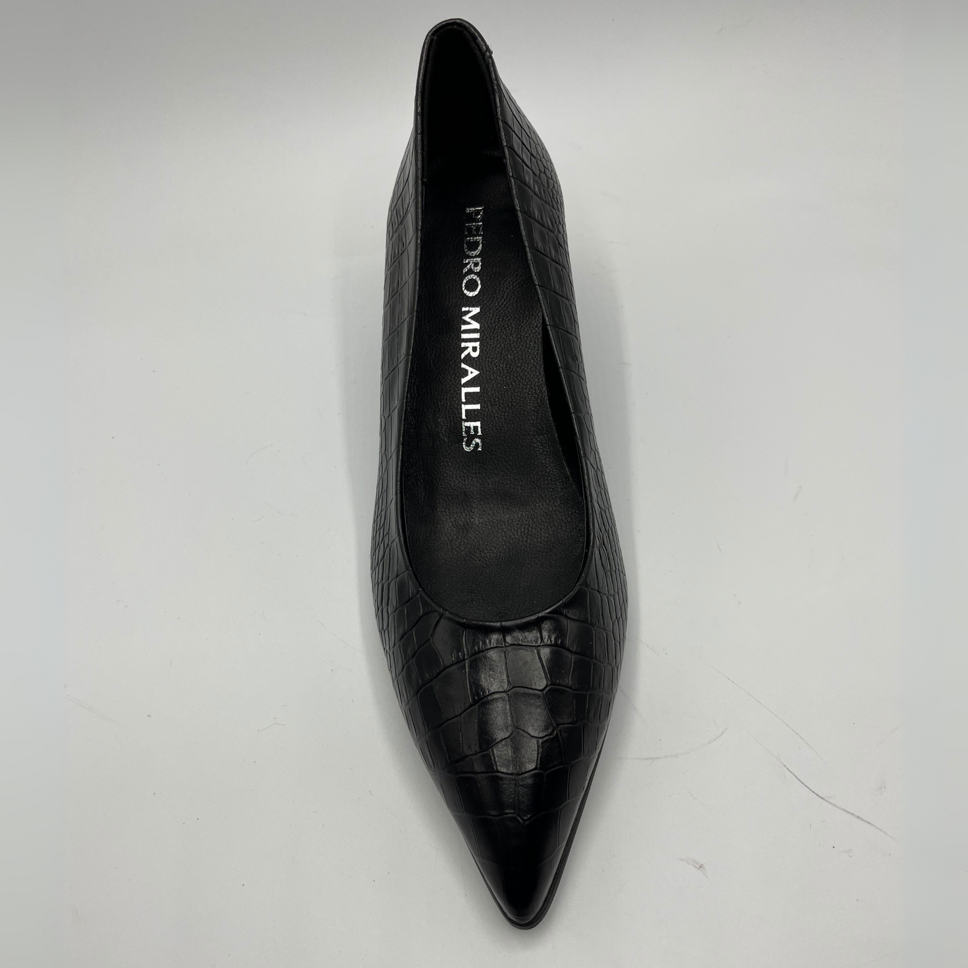 Black pointed-toe shoe with 'Pedro Miralles' branding on a light gray background
