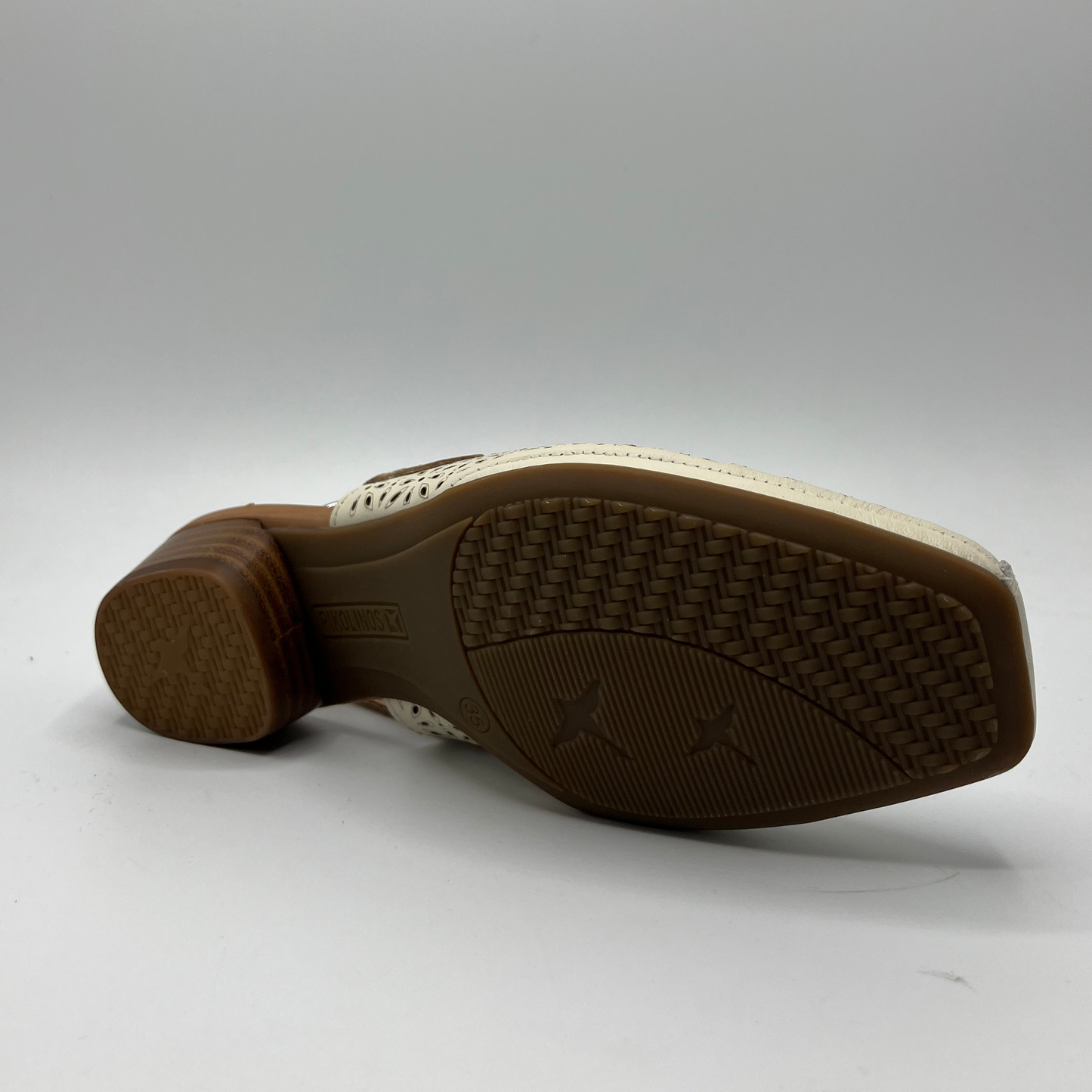 Bottom view of a die cut leather shoe with a short stacked heel and an adjustable slingback strap.