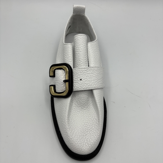 Top view of a white leather shoe with a gold buckle