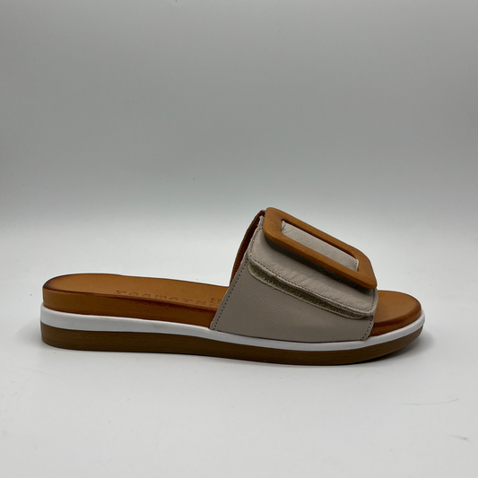 Right facing view of a leather slip on sandal with an adjustable silver grey strap, a tan decorative buckle, leather lining and contoured footbed.