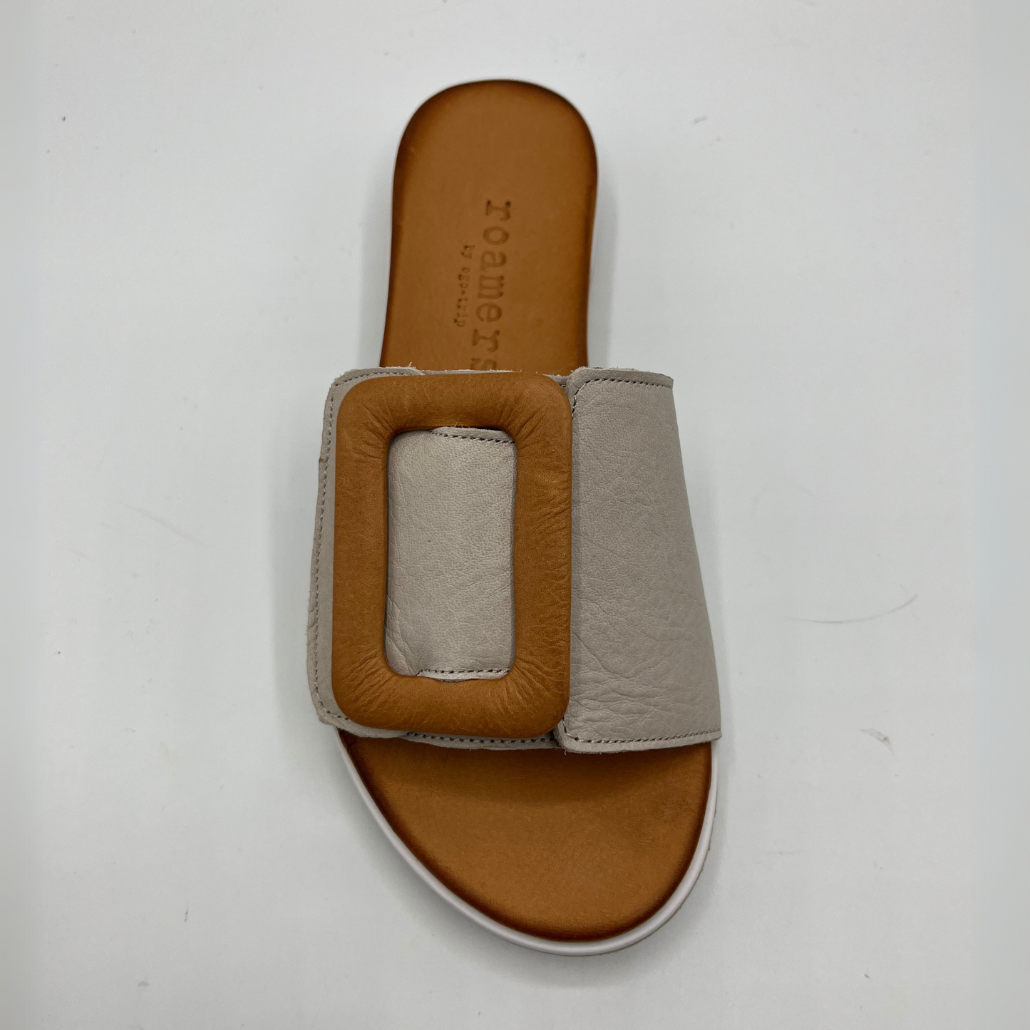Top view of a leather slip on sandal with an adjustable silver grey strap, a tan decorative buckle, leather lining and contoured footbed.