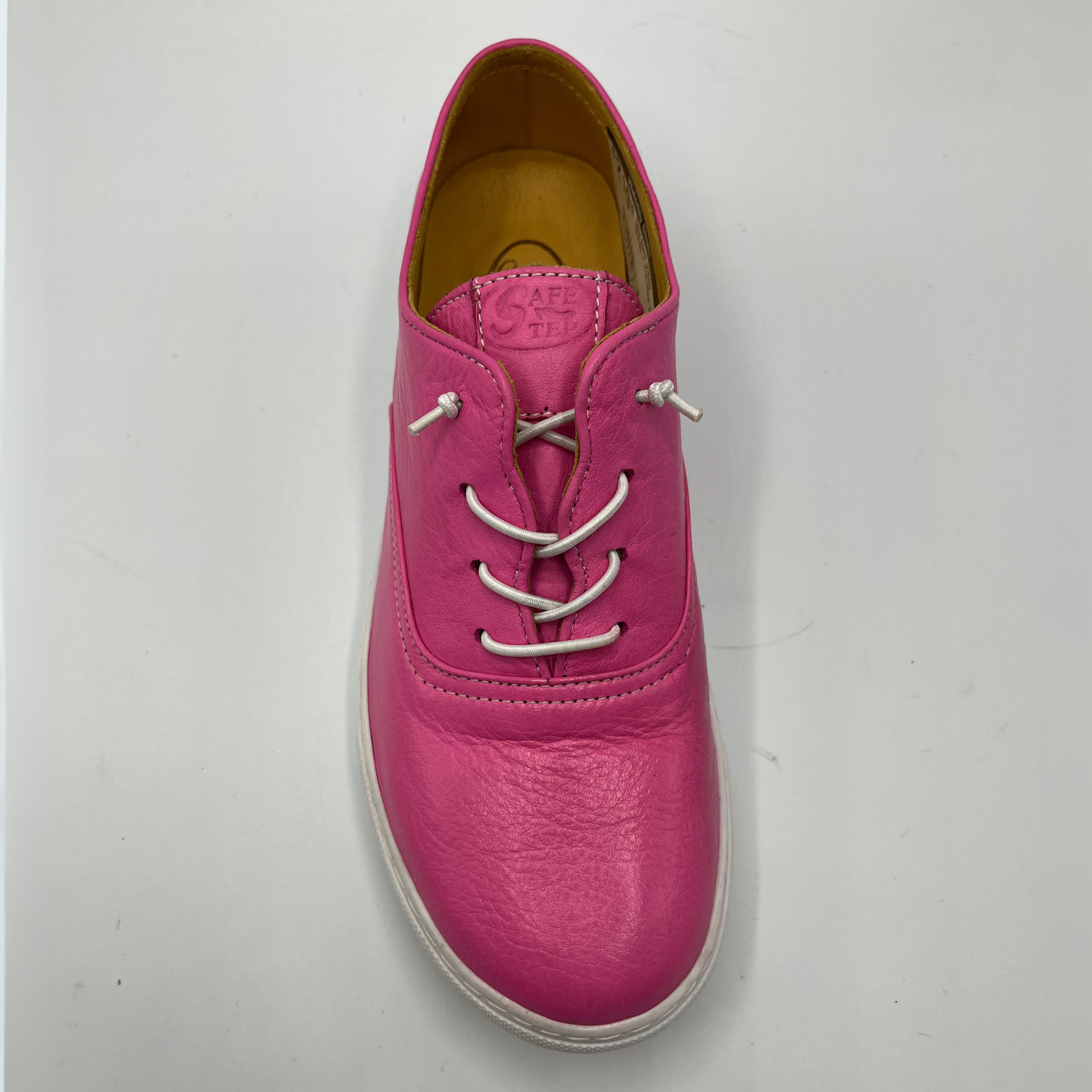 Top view of a fuschia leather sneaker with elastic laces and a white rubber outsole.