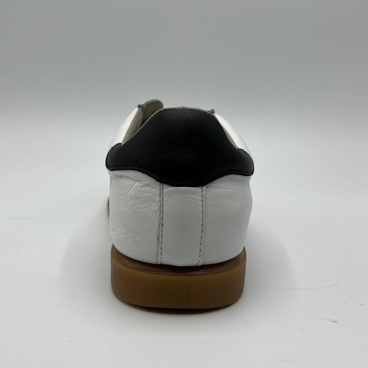 Back view of a leather and suede sneaker with a brown rubber outsole and a padded collar.
