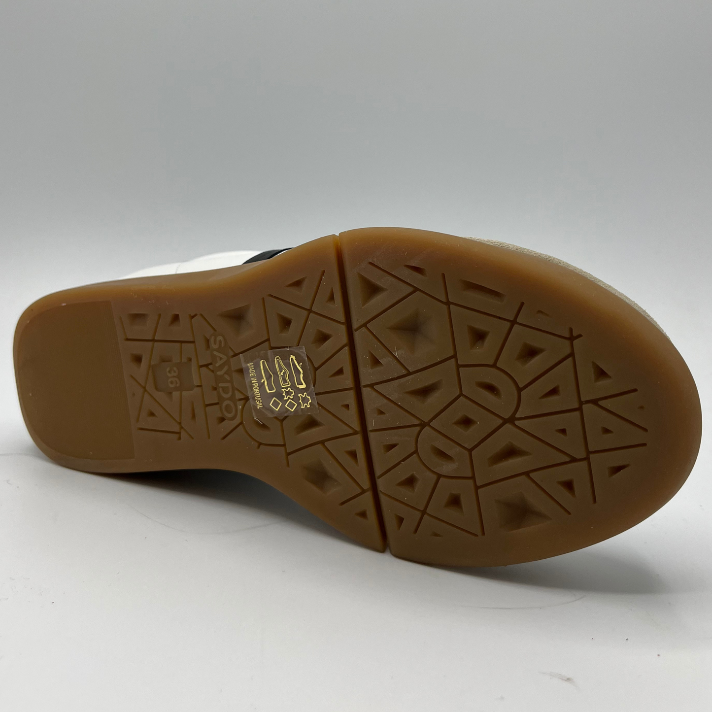 Bottom view of a leather and suede sneaker with a brown rubber outsole and a padded collar.