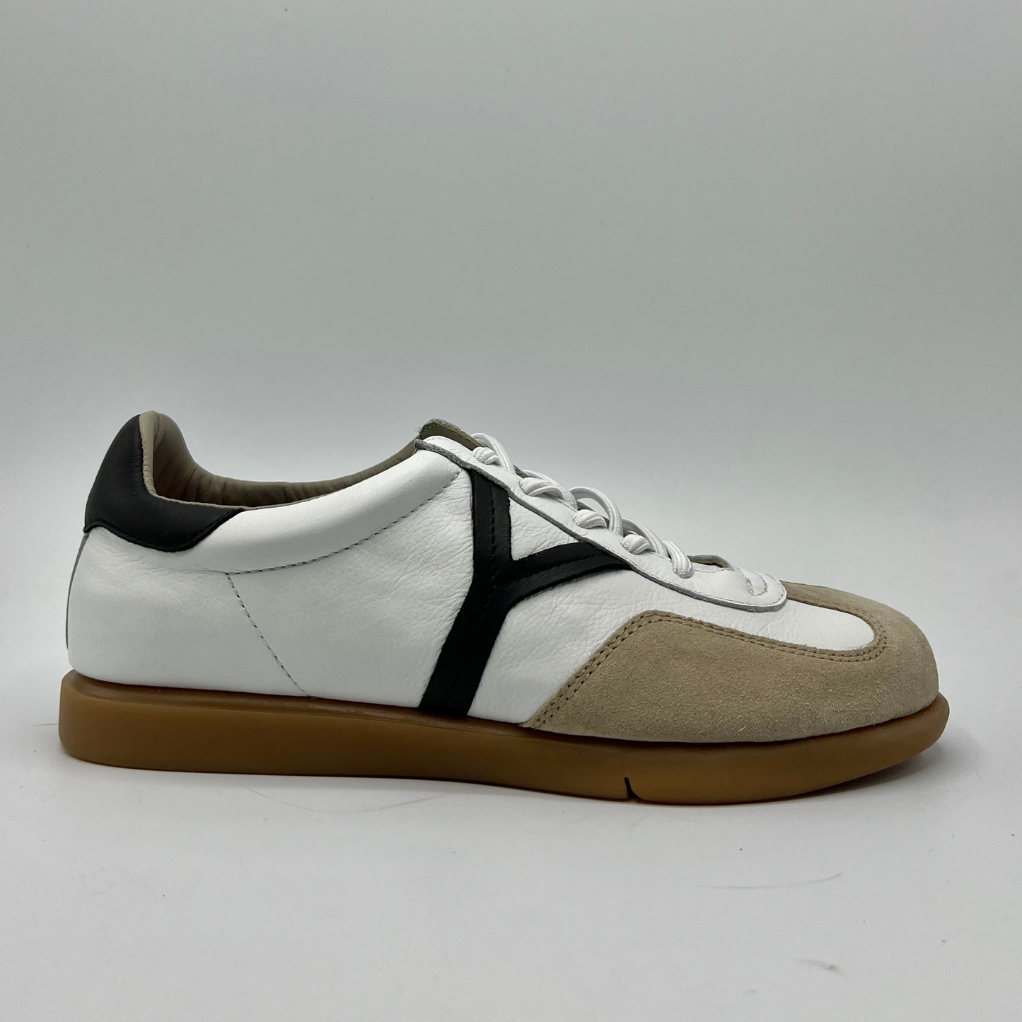 Right facing view of a leather and suede sneaker with a brown rubber outsole and a padded collar.