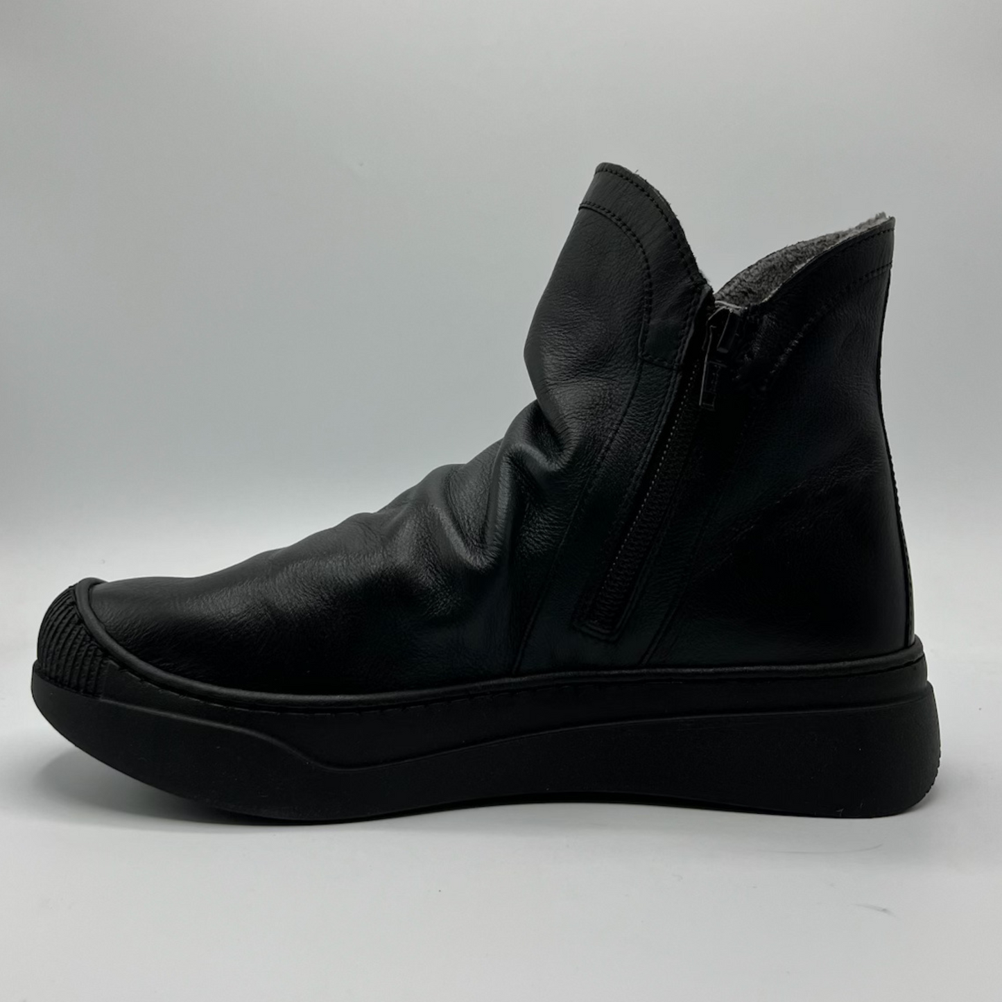 Black leather boot on a gray background