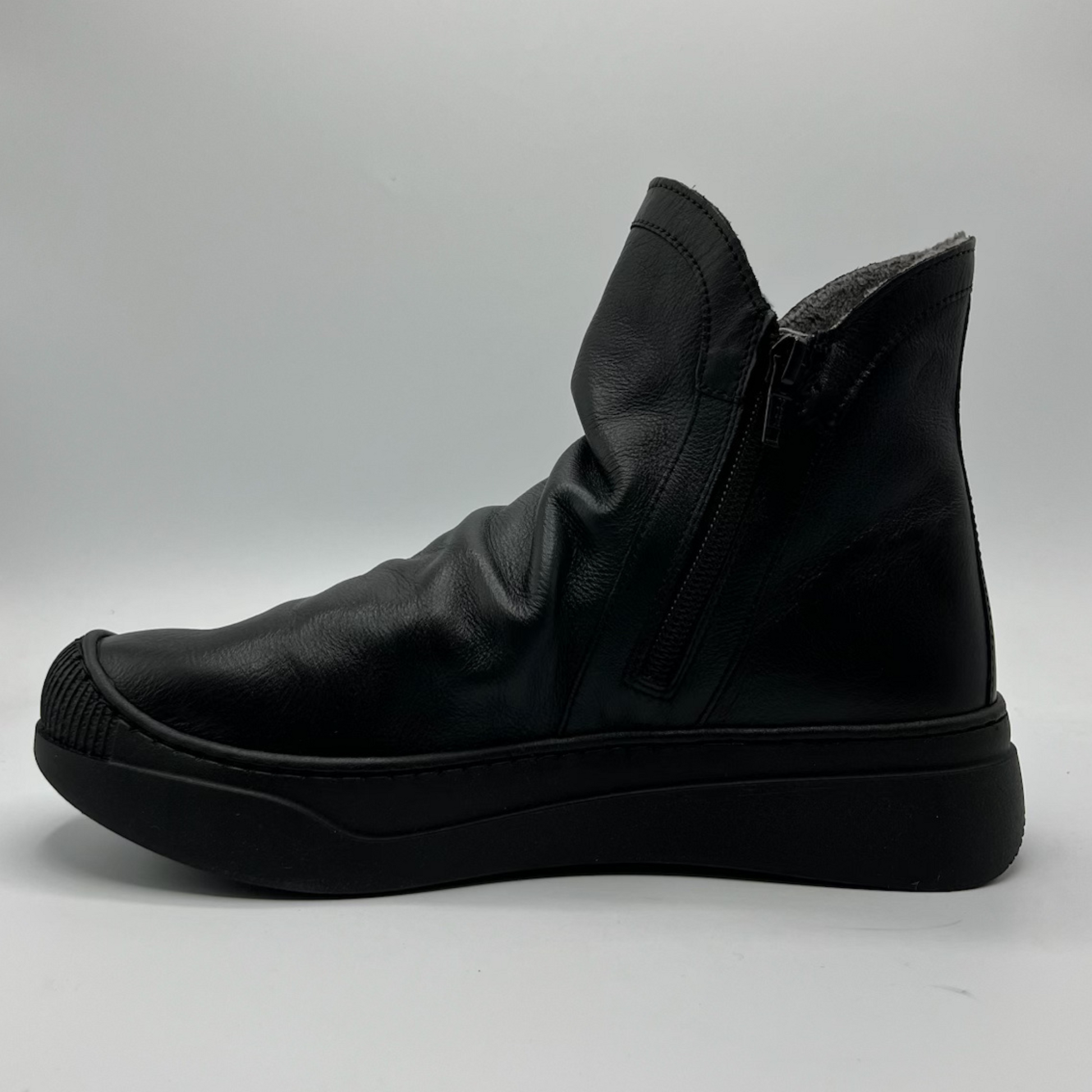 Black leather boot on a gray background