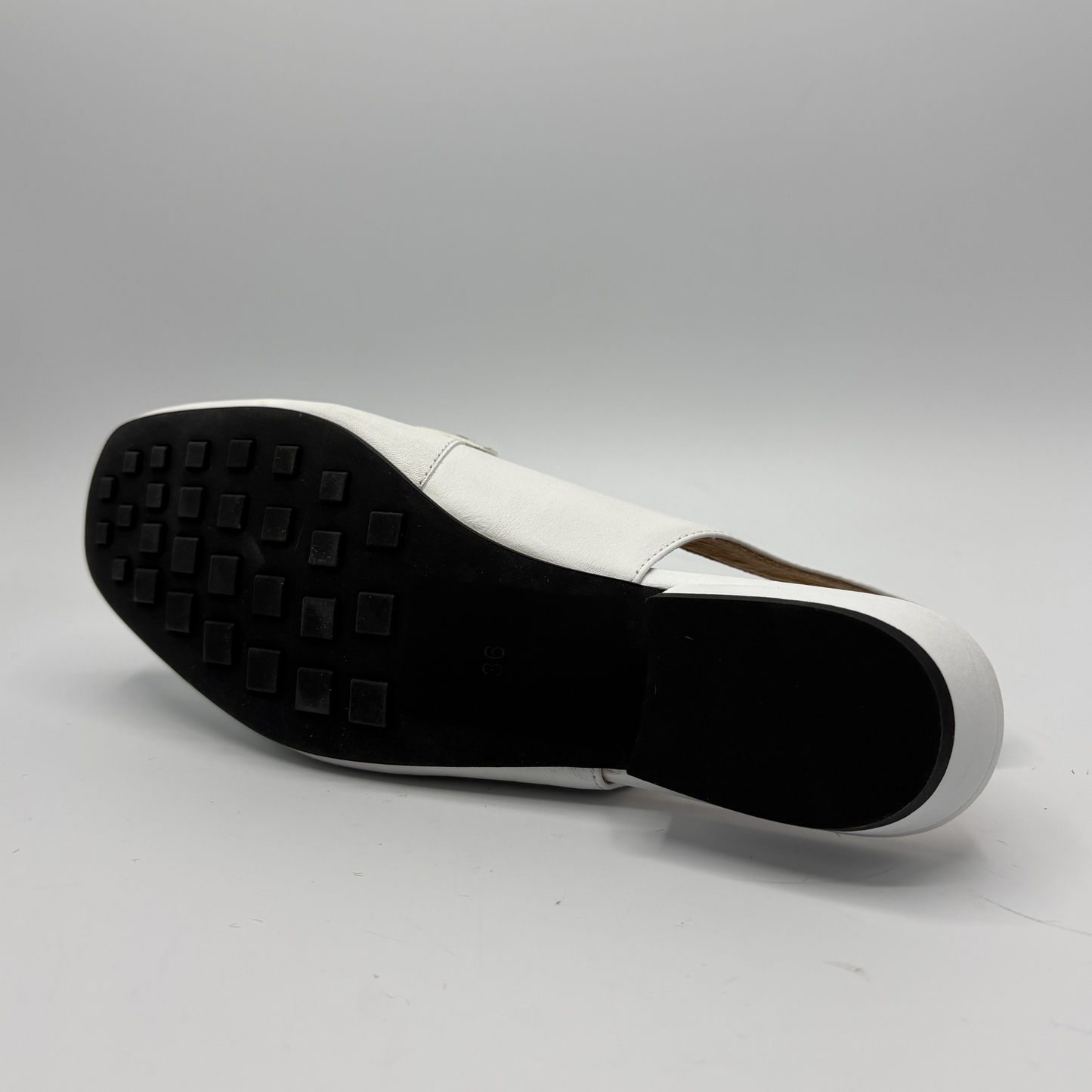 White shoe sole with black tread pattern on a gray background