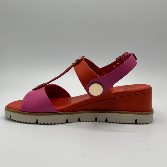 Left facing view of a fuschia and orange leather sandal with a wedge heel, adjustable ankle strap and shiny gold details.