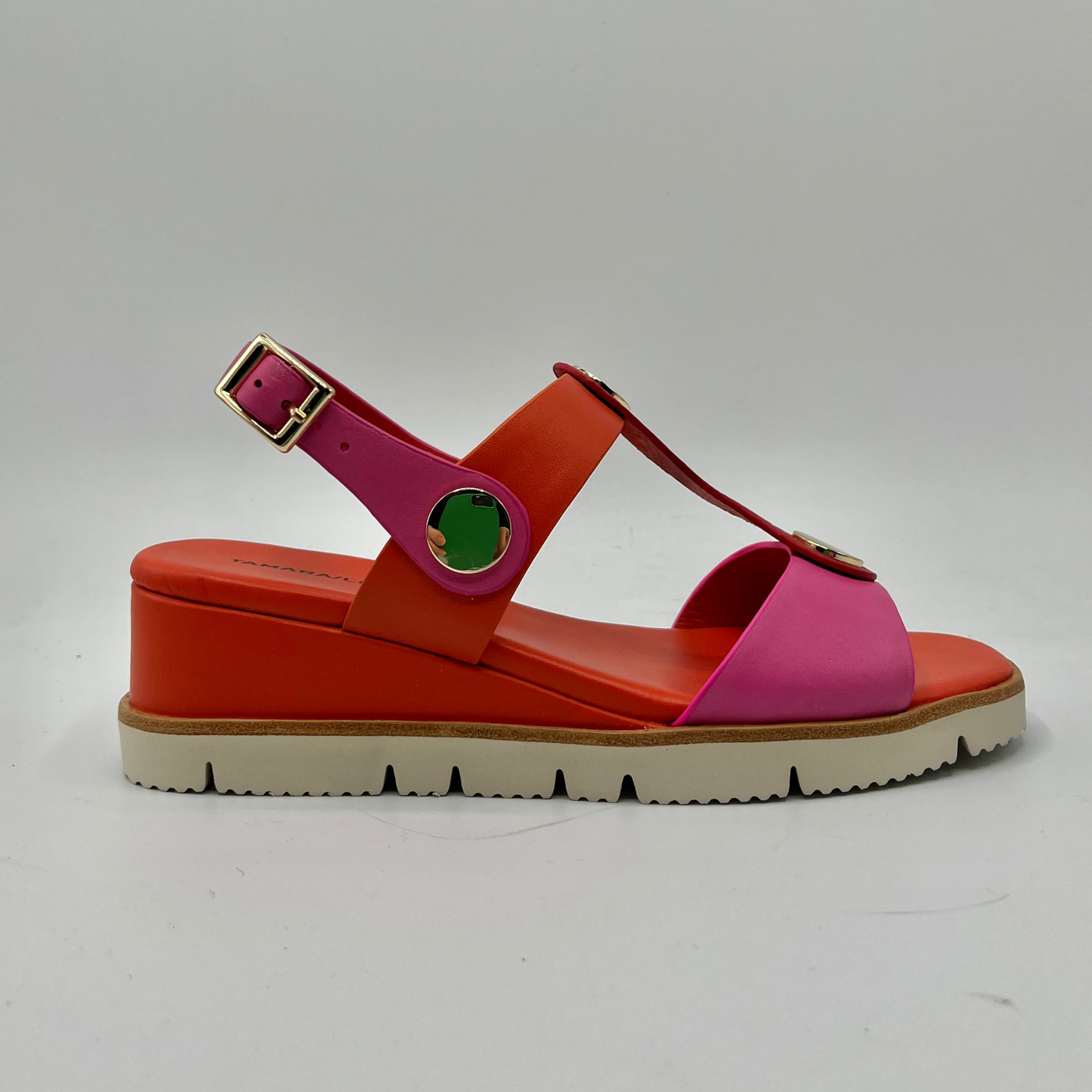 Right facing view of a fuschia and orange leather sandal with a wedge heel, adjustable ankle strap and shiny gold details.